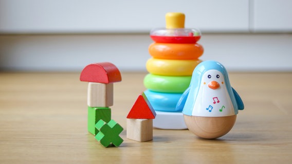 Spielzeug, bestehend aus einem Pinguin, Klötzen und einem bunten Ring-Turm auf dem Boden © NDR Foto: Elke Janning