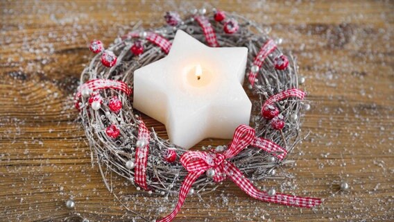 Adventskranz aus Weidengeflecht mit einer weißen Kerze in Sternenform und einer rot-weißen Schleife. © picture alliance / blickwinkel Foto: P. Frischknecht