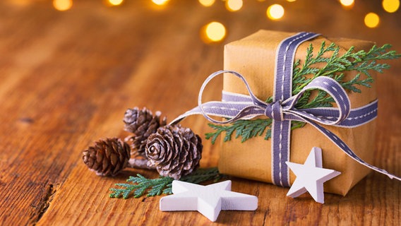 Ein Weihnachtsgeschenk und Sterne auf einer Holzplatte © Fotolia Foto: Floydine