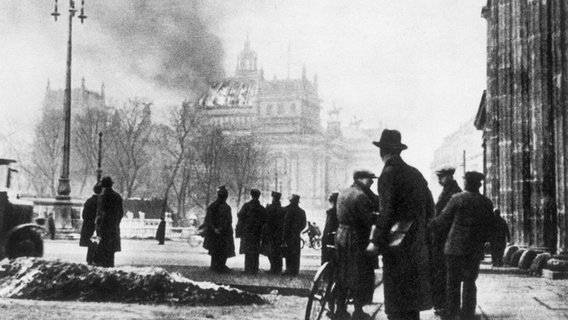 Blick vom Brandenburger Tor auf das brennende Reichstagsgebäude am Morgen des 28. Februar 1933. In der Nacht vom 27. auf den 28. Februar 1933 wurde das Reichstagsgebäude durch Brandstiftung größtenteils zerstört. Blick vom Brandenburger Tor auf das brennende Reichstagsgebäude am Morgen des 28. Februar 1933. In der Nacht vom 27. auf den 28. Februar 1933 wurde das Reichstagsgebäude durch Brandstiftung größtenteils zerstört. © picture-alliance / akg-images