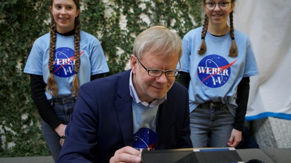 Zum letzten Mal wird die Technik von Wulf-Gerd Traving überprüft. Annika (links) und Leonie (rechts) unterstützen den Amateur Funker dabei. Zum letzten Mal wird die Technik von Wulf-Gerd Traving überprüft. Annika (links) und Leonie (rechts) unterstützen den Amateur Funker dabei. © NDR Foto: Marina Heller