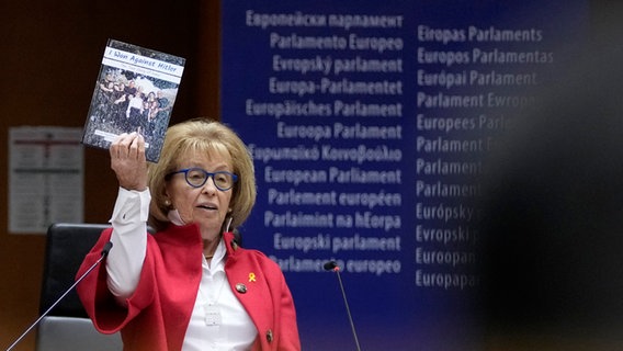 Irene Shashar, eine Überlebende des Warschauer Ghettos, hält ein Buch hoch, das sie über ihr Leben geschrieben hat, als sie vor der Plenarsitzung des Europäischen Parlaments zum Holocaust-Gedenktag spricht. © AP Foto: Virginia Mayo