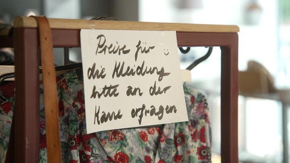 Ein Schild mit der Aufschrift "Preise für die Kleidung bitte an der Kasse erfragen". © NDR Foto: NDR