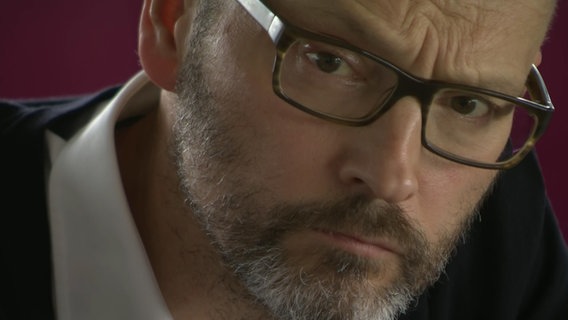 "Spiegel"-Chefredakteur Klusmann (Jahrgang 1966) schaut betrübt in die Kamera. Er trägt eine braune Brille und einen Vollbart. © NDR Foto: Screenshot