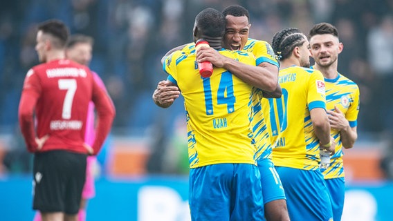 Braunschweigs Anthony Ujah (vorne) und Anton Donkor bejubeln den Sieg gegen Hannover. © picture alliance/dpa | Swen Pförtner 