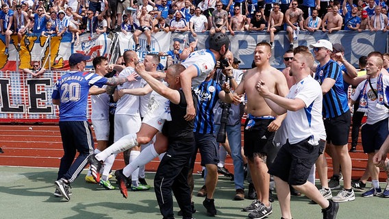 Rostocks Spieler feiern mit den mitgereisten Fans den Klassenerhalt © IMAGO / HMB-Media 