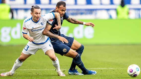 Rostocks Junior Brumado (r.) und Magdeburgs Baris Atik kämpfen um den Ball. © picture alliance/dpa | Andreas Gora 