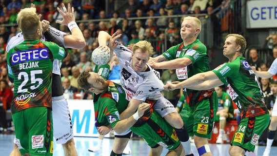 Kiels Eric Johansson (M.) versucht sich gegen die Magdeburger Defensive durchzusetzen. © IMAGO / Jan Huebner 