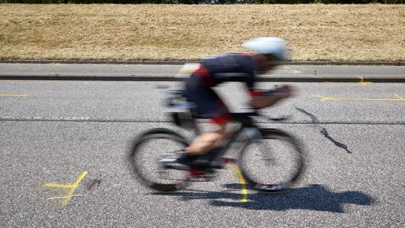 Triathleten fahren auf dem Rad an der Unglückstelle auf dem Deich vorbei. © picture alliance/dpa Foto: Georg Wendt