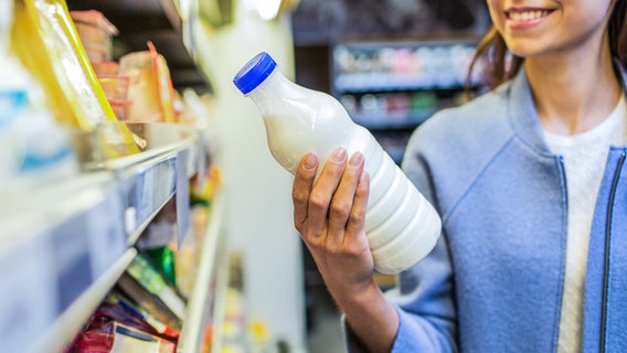 Junge Frau betrachtet eine Milchflasche im Supermarkt. © SydaProductions, fotolia Foto: SydaProductions