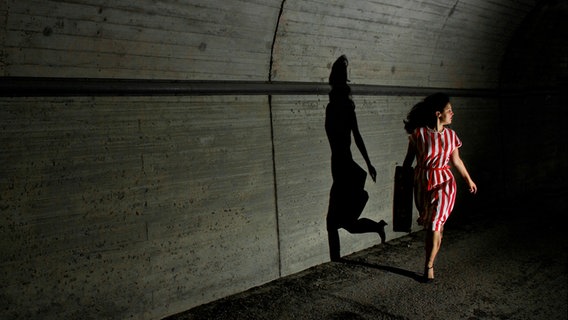 Eine Frau läuft durch einen dunklen Tunnel. © Photocase Foto: pixelhans