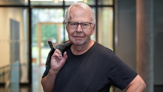 Harald Maack hängt seine Jacke über die Schulter. © NDR Foto: Frederike Burgdorf