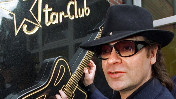 Udo Lindenberg zupft am 22.6.1997 symbolisch an der Gitarre, die Teil des gerade enthüllten Gedenksteins für den Hamburger Star-Club ist. © dpa Foto: Kay Nietfeldt