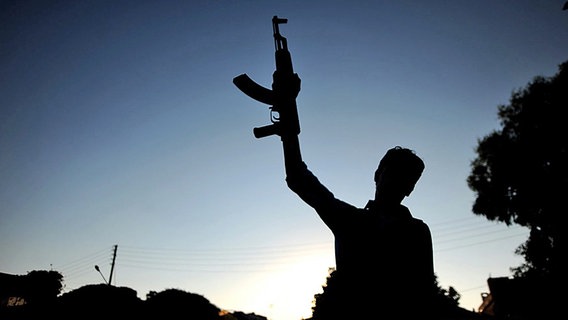 Mann in Syrien hält eine Waffe in die Luft. © dpa bildfunk 