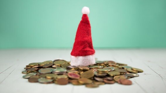 Eine kleine Weihnachtsmütze auf einem Haufen Münzgeld © photocase.de Foto: David W