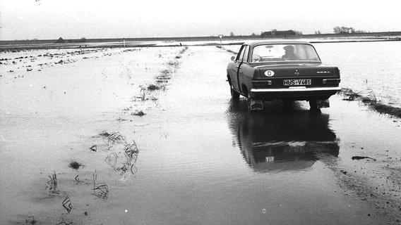 Altes Bild aus dem Kreisarchiv Nordfriesland, das ein Auto auf dem überfluteten Marschboden zeigt. © Kreisarchiv Nordfriesland 