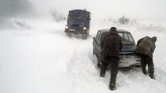 Zwei Männer schieben ein Auto an, das im Schnee stecken geblieben ist. © picture alliance / Werner Baum 